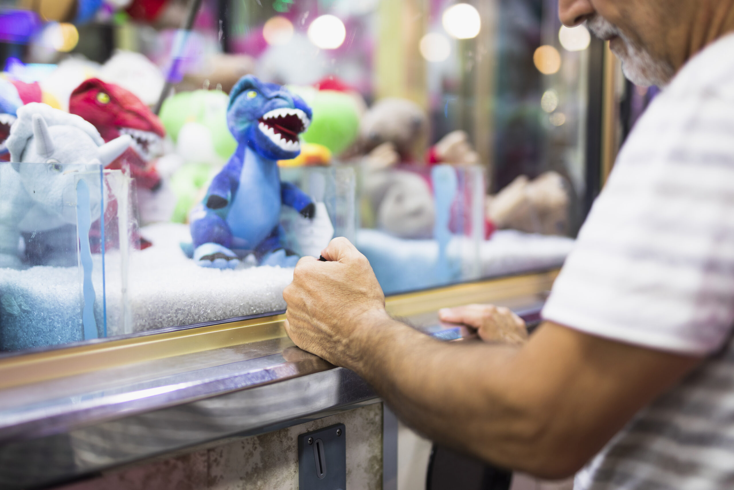 older-man-playing-toy-claw-machine